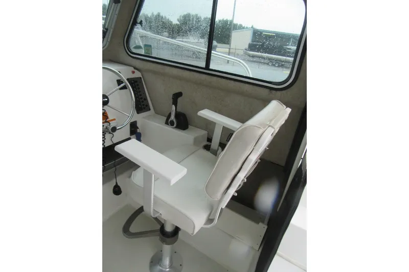 Slide: The Image of Captain's chair inside 2016 Parker 2120 Sport Cabin boat, featuring steering wheel and controls. - 23