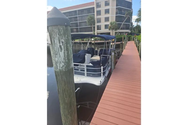 The Image of 2021 Hurricane FunDeck 216 OB docked beside a wooden pier, with a building in the background. - 1