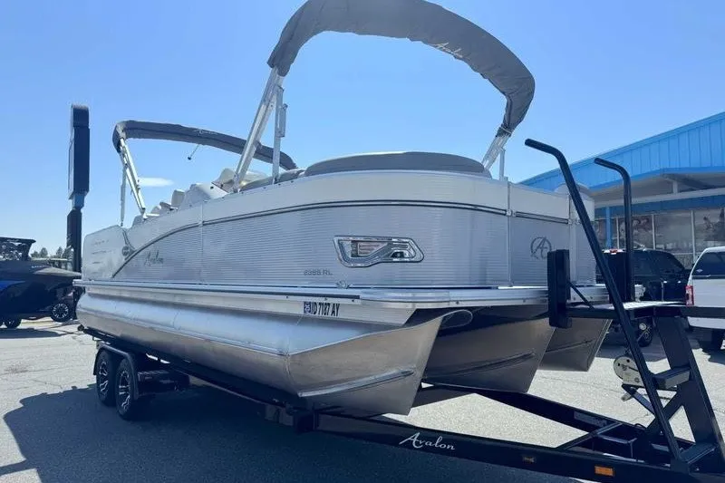 Slide: The Image of 2019 Avalon Catalina Rear Lounge 25' pontoon boat on trailer, parked outdoors. - 8
