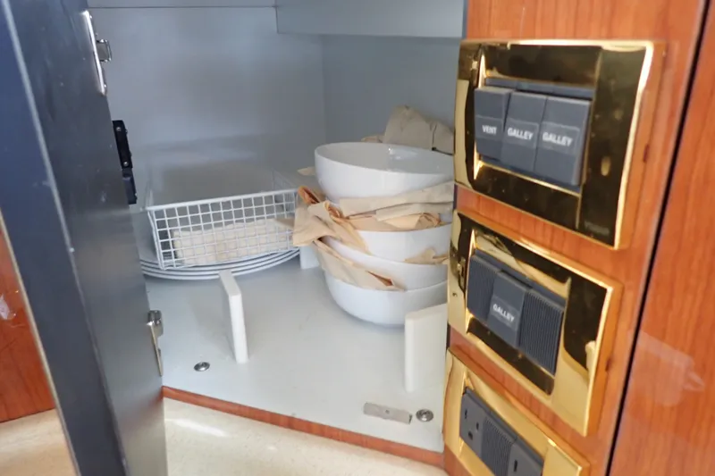 Slide: The Image of Cabinet interior with dishes and switches on a 1998 Sea Ray 480 Sedan Bridge yacht. - 111