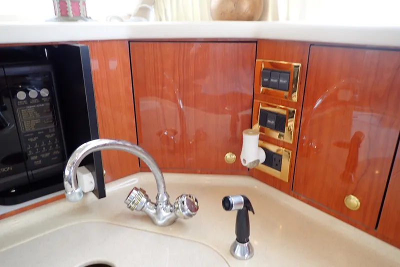 Slide: The Image of Luxury yacht kitchen with wood cabinets, chrome faucet, and control panel on a 1998 Sea Ray 480 Sedan Bridge. - 110