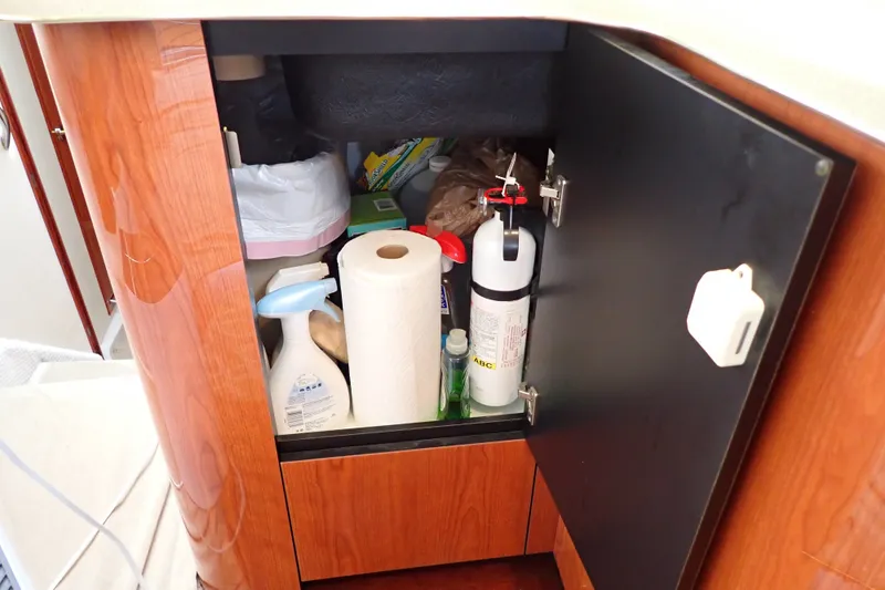 Slide: The Image of Open cabinet on 1998 Sea Ray 480 Sedan Bridge, storing cleaning supplies and a fire extinguisher. - 115