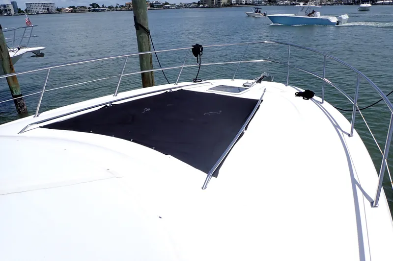 Slide: The Image of 1998 Sea Ray 480 Sedan Bridge yacht bow view, docked in a serene marina setting. - 4