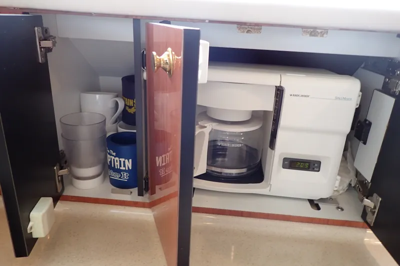 Slide: The Image of Coffee maker and mugs inside a cabinet on a 1998 Sea Ray 480 Sedan Bridge. - 113
