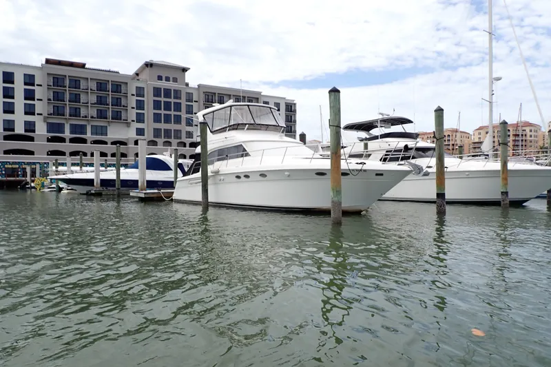 Slide: The Image of 1998 Sea Ray 480 Sedan Bridge yacht docked at marina with waterfront buildings. - 211