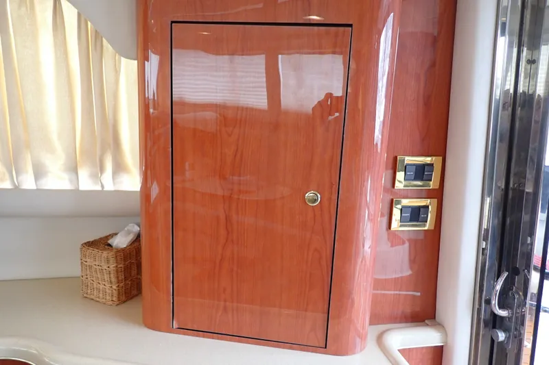 Slide: The Image of Interior of 1998 Sea Ray 480 Sedan Bridge with wooden cabinet and control switches. - 128