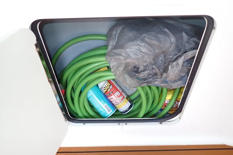 Slide: The Image of Storage compartment on a 1998 Sea Ray 480 Sedan Bridge with hose and cleaning supplies. - 76