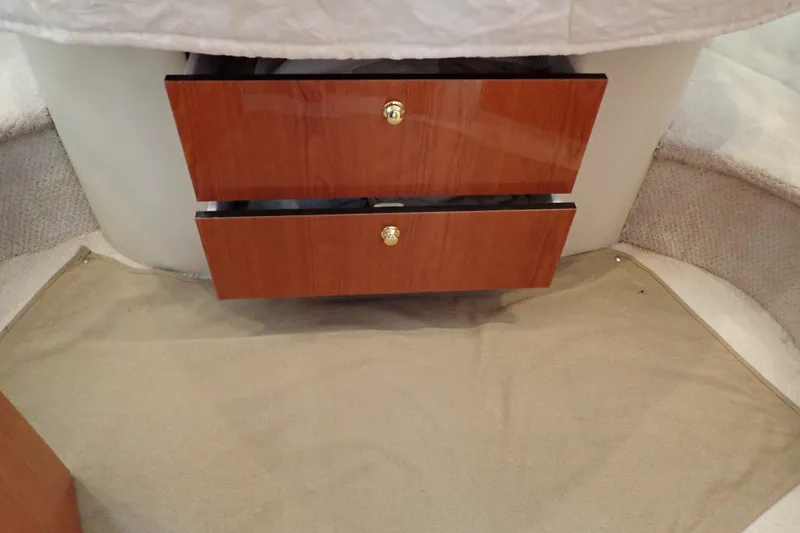Slide: The Image of Interior view of 1998 Sea Ray 480 Sedan Bridge with wooden drawers and beige carpet. - 173