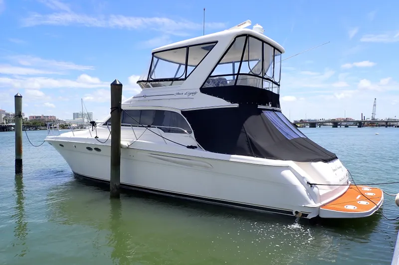 The Image of 1998 Sea Ray 480 Sedan Bridge yacht docked in a marina under a clear blue sky. - 0