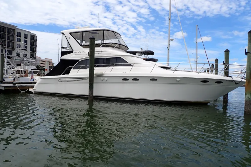 Slide: The Image of 1998 Sea Ray 480 Sedan Bridge yacht docked in marina, under clear blue sky. - 1