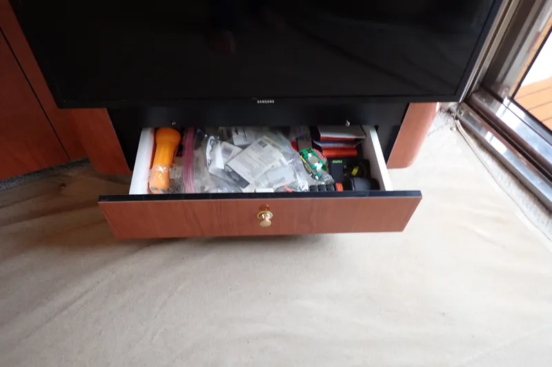 Slide: The Image of Open drawer under TV on 1998 Sea Ray 480 Sedan Bridge, containing various items. - 127