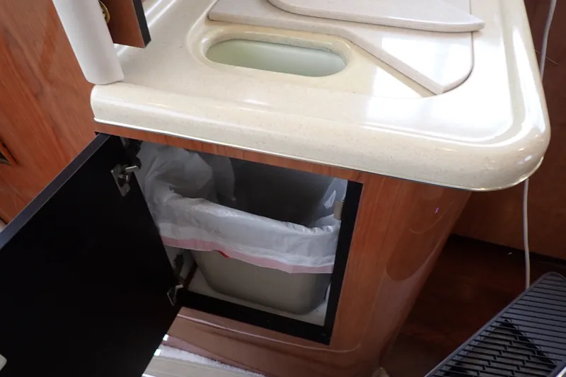 Slide: The Image of Kitchen area of a 1998 Sea Ray 480 Sedan Bridge with trash bin under counter. - 134