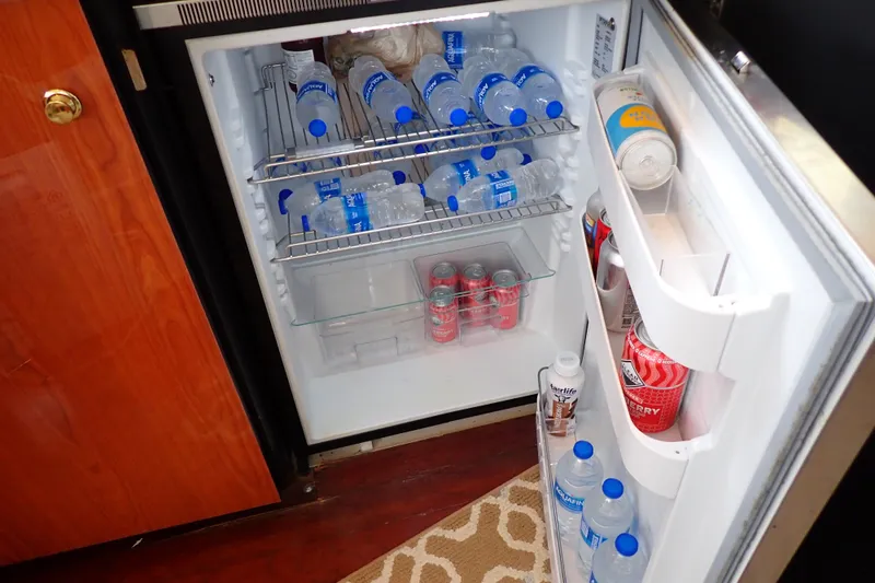 Slide: The Image of Mini fridge stocked with water bottles and soda cans on a 1998 Sea Ray 480 Sedan Bridge. - 109