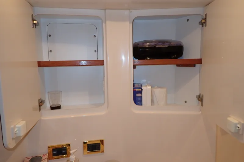 Slide: The Image of Open cabinet in 1998 Sea Ray 480 Sedan Bridge yacht bathroom, showing shelves with toiletries. - 155