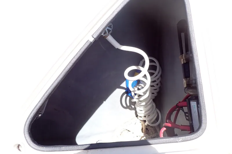 Slide: The Image of Storage compartment of 1998 Sea Ray 480 Sedan Bridge with coiled hose and wiring. - 96