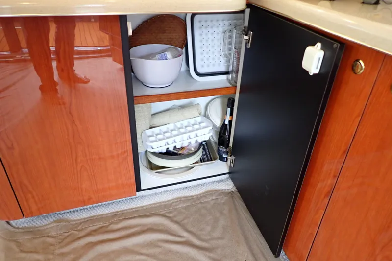 Slide: The Image of Open cabinet in 1998 Sea Ray 480 Sedan Bridge galley with kitchen items and storage. - 123