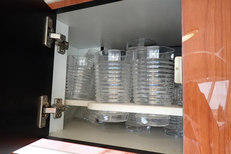 Slide: The Image of Plastic cups neatly stacked in a wooden cabinet on a 1998 Sea Ray 480 Sedan Bridge. - 121