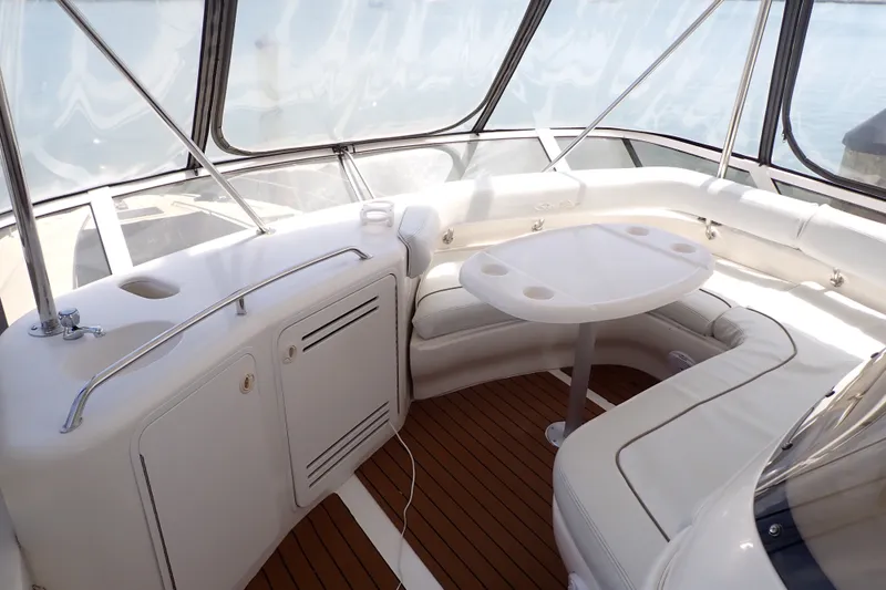 Slide: The Image of 1998 Sea Ray 480 Sedan Bridge interior with white seating and table, featuring wood flooring. - 9