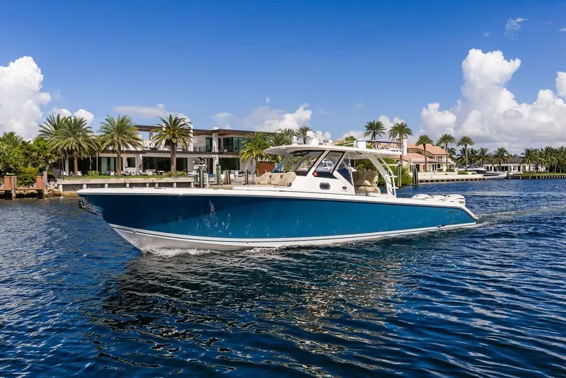 Slide: The Image of 2020 Pursuit S 408 Sport boat cruising on a sunny waterfront with palm trees. - 8