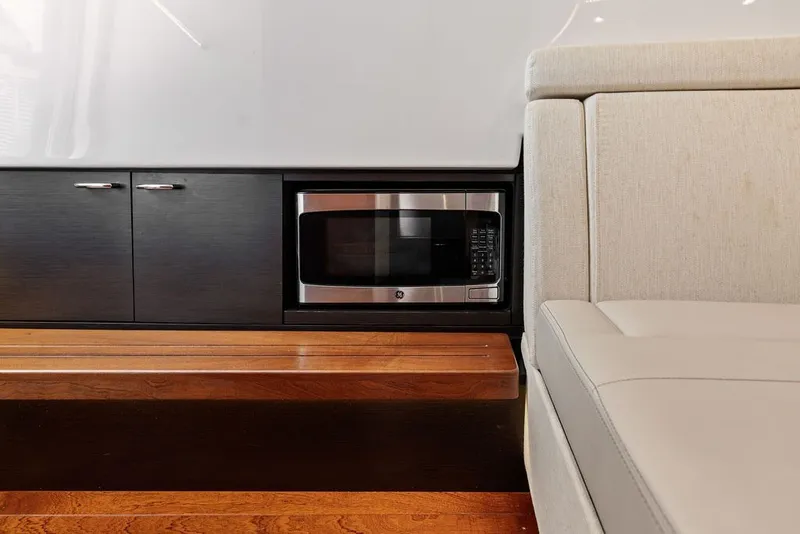 Slide: The Image of 2020 Pursuit S 408 Sport interior with microwave, cabinets, and beige seating. - 56