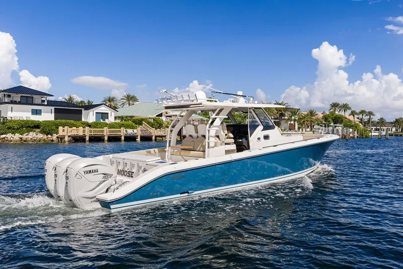 Slide: The Image of 2020 Pursuit S 408 Sport boat cruising on a sunny day near waterfront homes. - 14