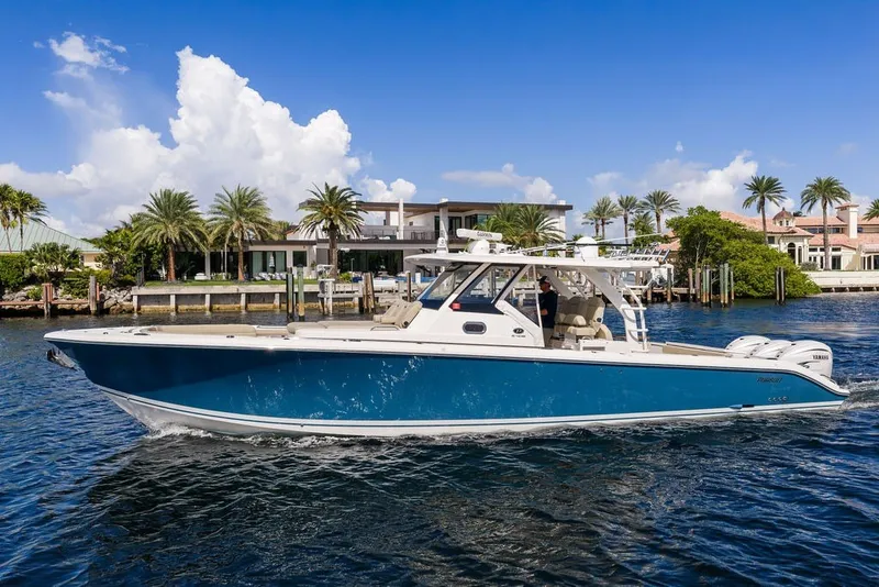 The Image of 2020 Pursuit S 408 Sport boat cruising on a sunny day near waterfront homes. - 0