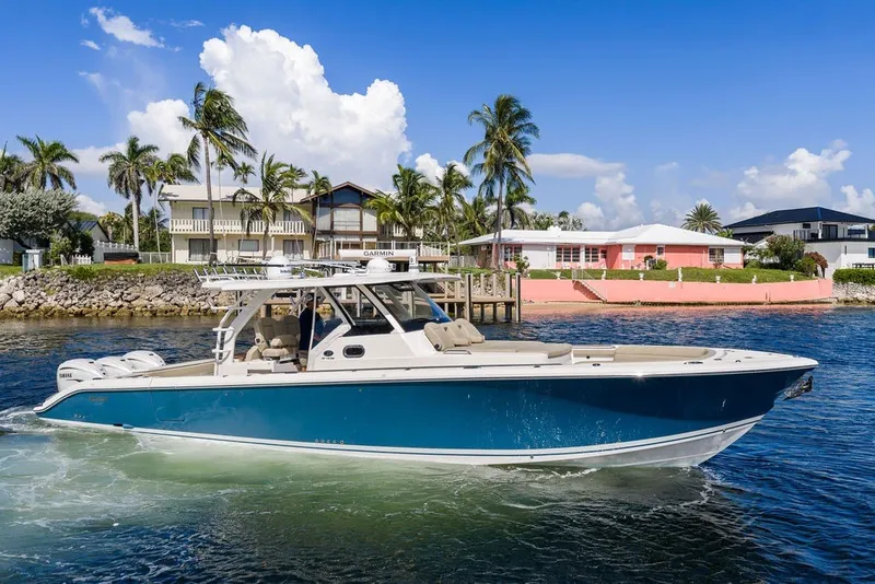 Slide: The Image of 2020 Pursuit S 408 Sport boat cruising near waterfront homes with palm trees. - 12