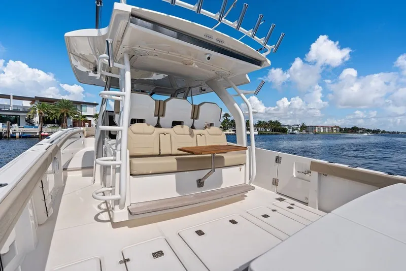 Slide: The Image of 2020 Pursuit S 408 Sport boat with seating, docked by waterfront homes under blue sky. - 23