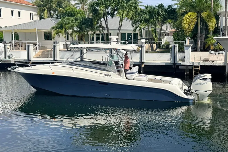 The Image of 2005 Hydra-Sports Vector 3300 VX boat docked by waterfront homes, featuring Suzuki outboard engine. - 0