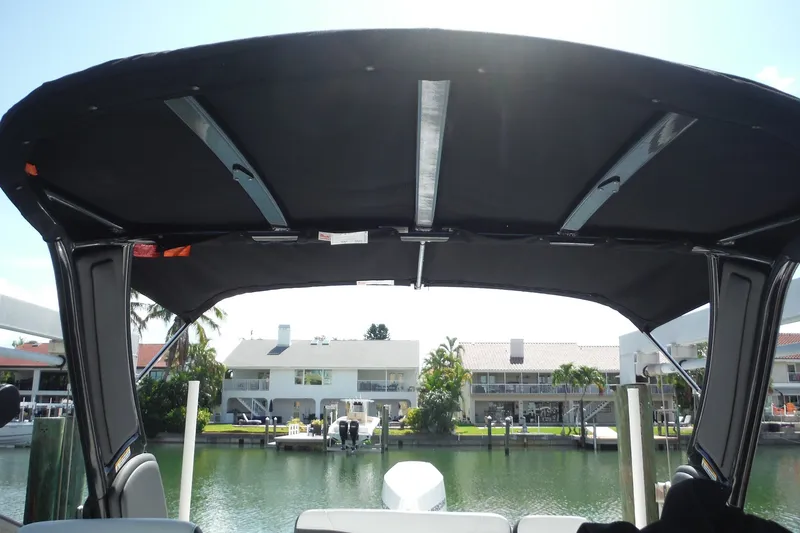Slide: The Image of 2024 Monterey 255SS Super Sport boat interior with canopy, docked by waterfront homes. - 33