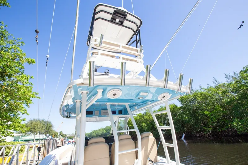 Slide: The Image of 2020 Everglades 365 Center Console boat with fishing rod holders, docked by lush greenery. - 14