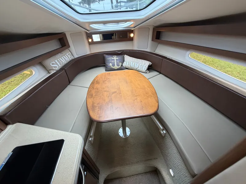 Slide: The Image of Interior of a 2014 Sea Ray Sundancer 280 with a wooden table and cushions. - 30