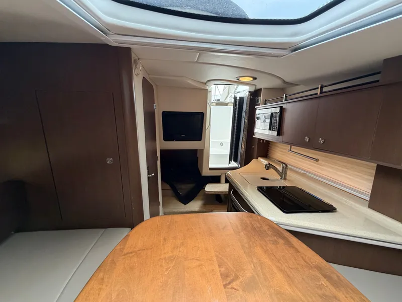 Slide: The Image of Interior of a 2014 Sea Ray Sundancer 280 with a kitchenette, table, and seating area. - 34