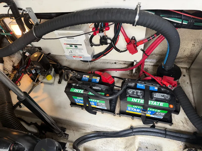 Slide: The Image of The engine compartment of a 2014 Sea Ray Sundancer 280 shows batteries and wiring. - 42