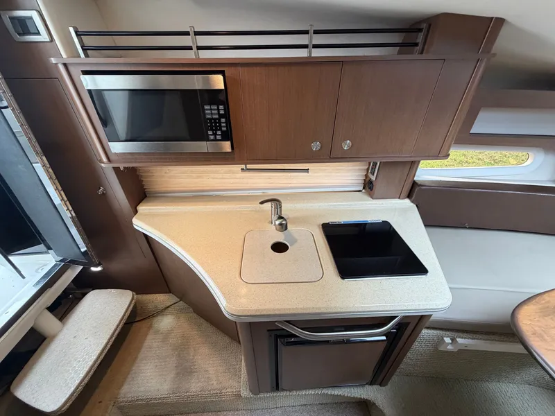 Slide: The Image of The galley of a 2014 Sea Ray Sundancer 280 with a microwave, sink, and cabinets. - 31