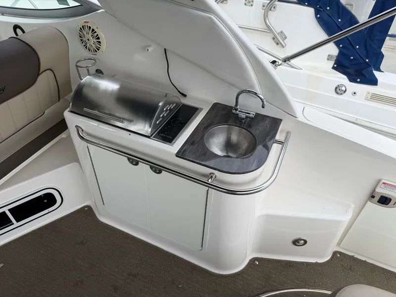 Slide: The Image of The 2014 Sea Ray Sundancer 280 features an outdoor kitchenette with a grill and sink. - 18