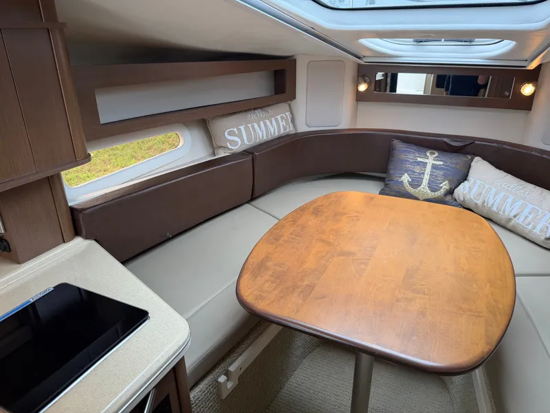 Slide: The Image of Interior of a 2014 Sea Ray Sundancer 280 with a wooden table and cushions. - 29