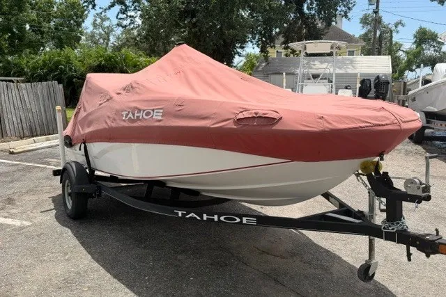 The Image of 2021 Tahoe T16 boat with cover on trailer in parking area. - 1