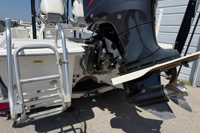 Slide: The Image of 2016 Blue Wave 2200 STL boat with outboard motor and ladder, parked near a metal building. - 9