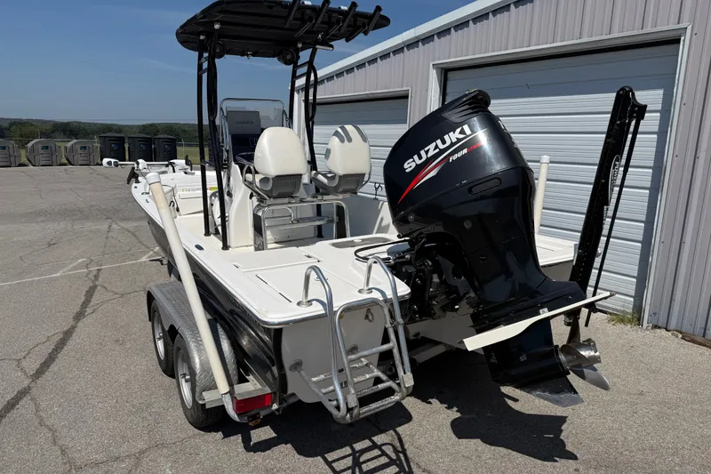 Slide: The Image of 2016 Blue Wave 2200 STL boat with Suzuki outboard motor, parked near a metal building. - 3