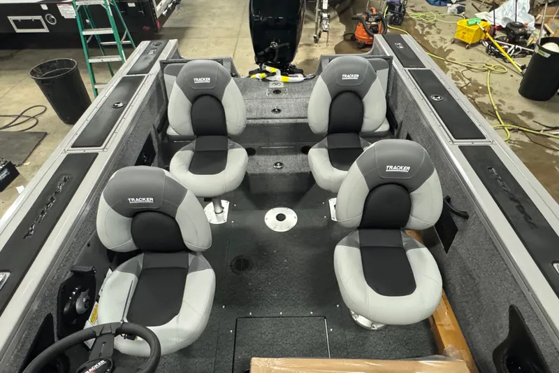 Slide: The Image of 2027 Tracker Targa V-18 Combo boat interior with four cushioned seats in a workshop setting. - 15