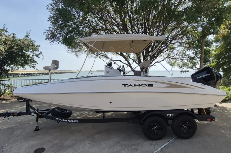 The Image of 2026 Tahoe 2150 CC boat on trailer by lakeside, featuring Mercury outboard motor. - 0