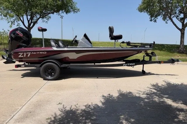 Slide: The Image of 2027 Nitro Z17 boat on trailer, parked outdoors under trees. - 24