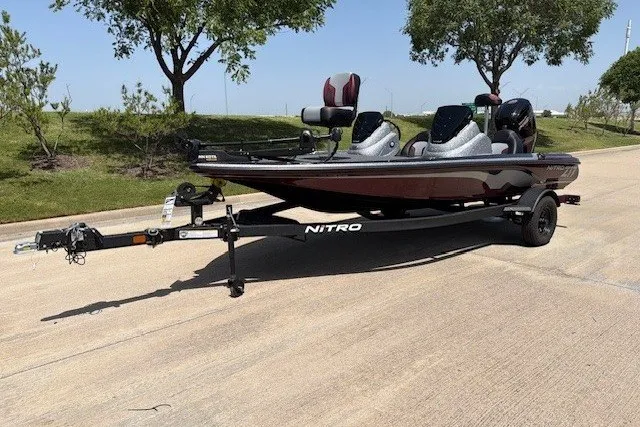 Slide: The Image of 2027 Nitro Z17 boat on trailer, parked on sunny road with trees. - 20