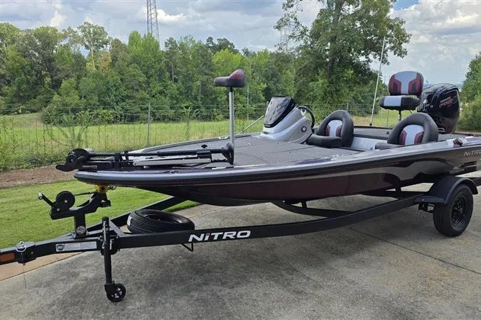 Slide: The Image of 2027 Nitro Z17 boat on trailer, parked outdoors with lush greenery background. - 6