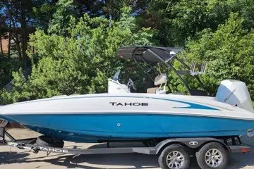 The Image of 2026 Tahoe 2150 CC boat on trailer, surrounded by lush greenery. - 0