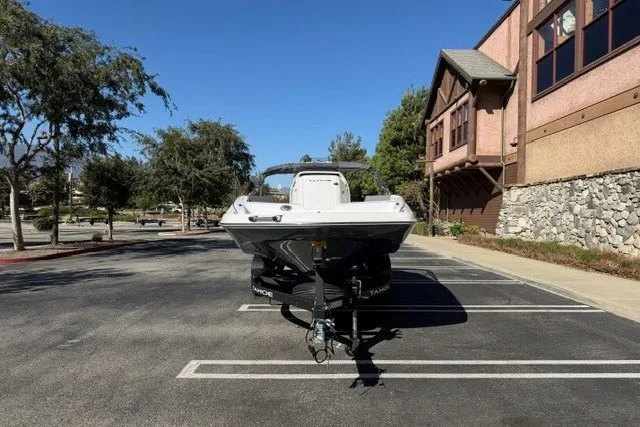 Slide: The Image of 2026 Tahoe 2150 CC boat on trailer in parking lot, sunny day, trees and building nearby. - 3