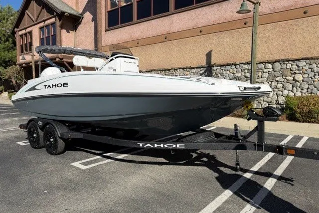 Slide: The Image of 2026 Tahoe 2150 CC boat on trailer, parked in a lot near a stone building. - 2