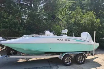 The Image of 2026 Tahoe 2150 CC boat on trailer, parked outdoors with lush greenery background. - 0