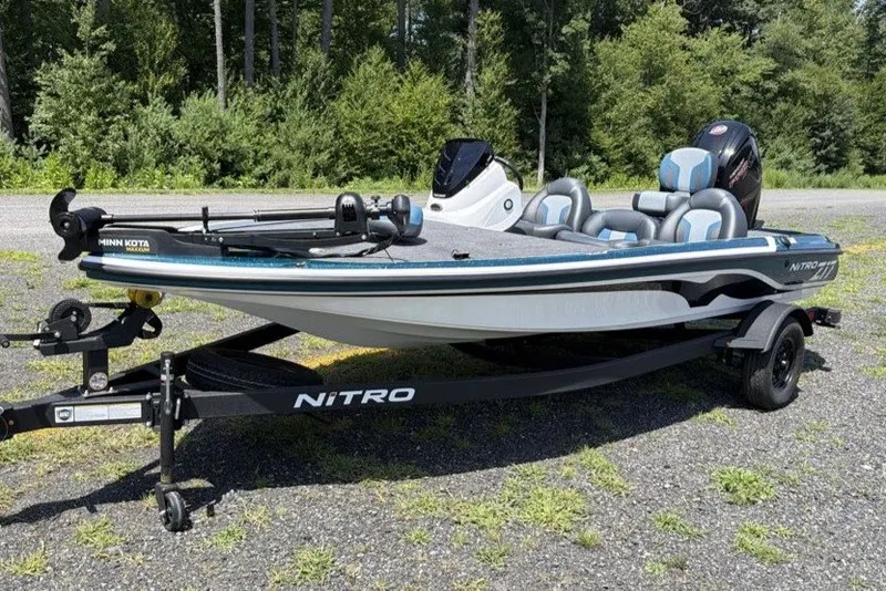 The Image of 2027 Nitro Z17 fishing boat on trailer, parked outdoors with lush green background. - 0